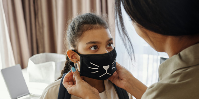 Mother putting a face mask on her daughter