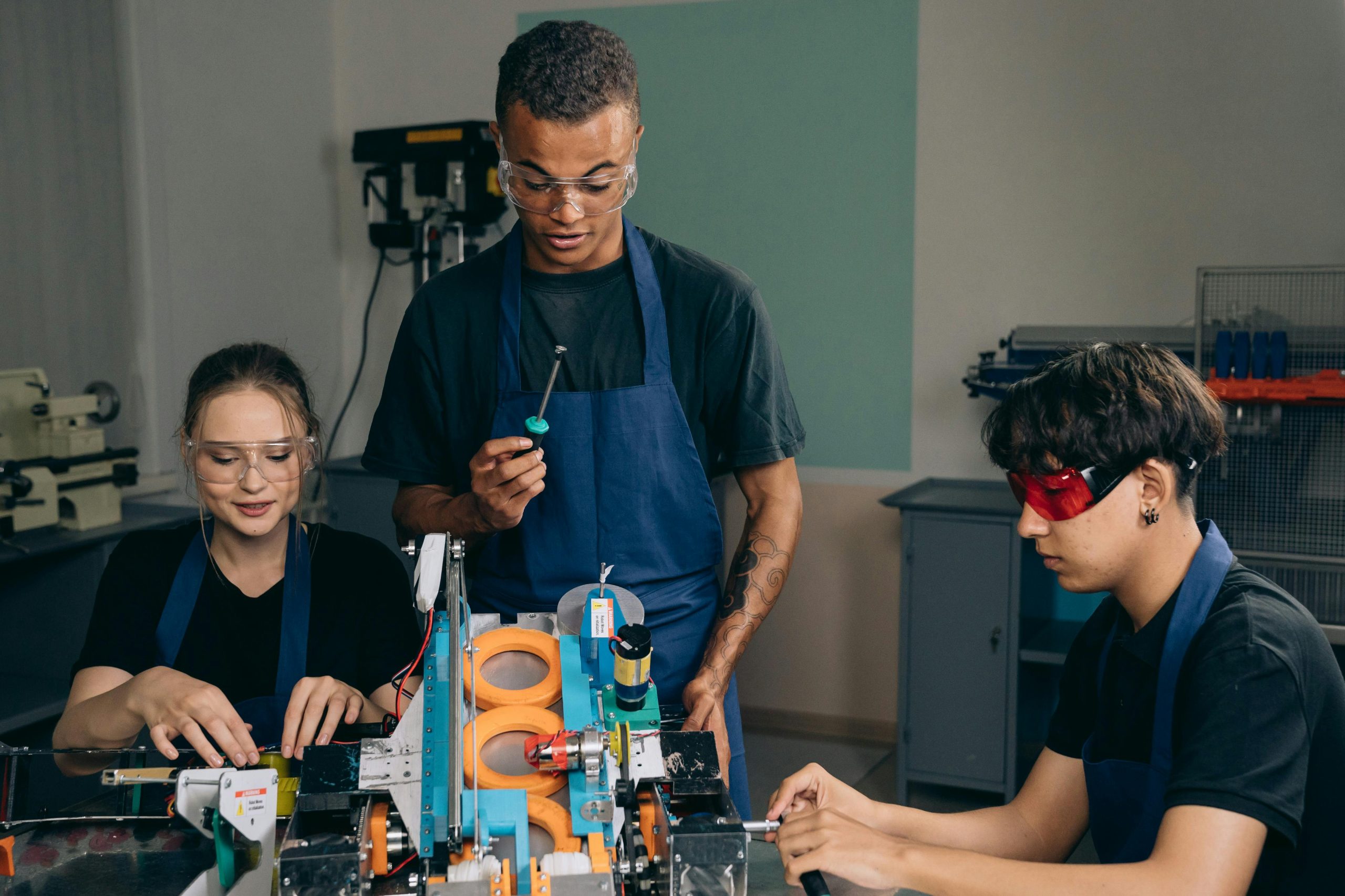 three students working on a project wearing safety glasses